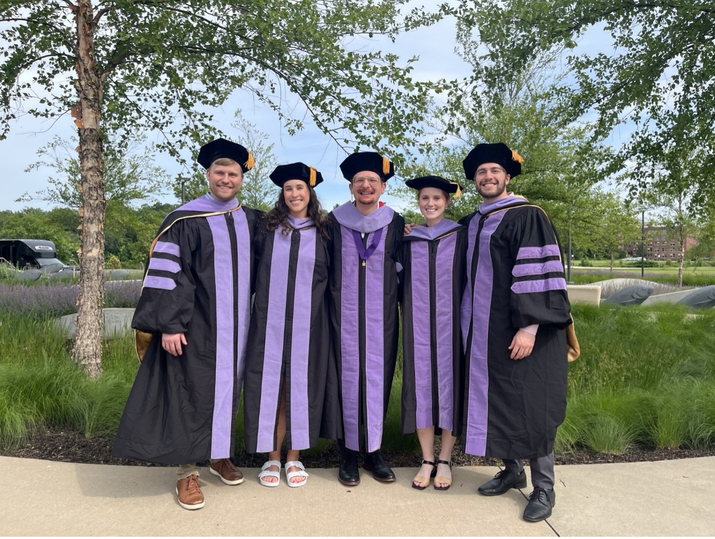 Class of 2024 graduates in black and lavender doctoral regalia