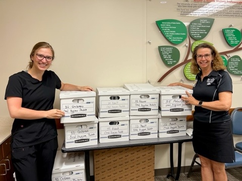 Pediatric dentistry student group co-president Sara Saey and faculty advisor Cathy Skotowski pictured with several boxes of the oral hygiene packets prior to delivery to DVIP.