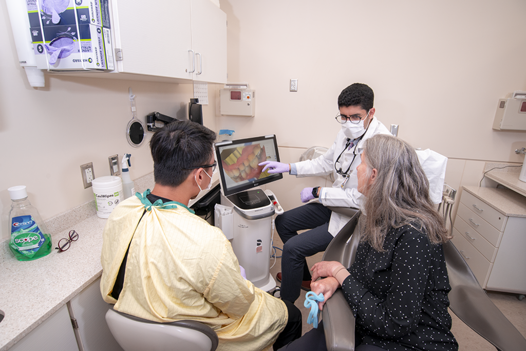 A dental faculty and dental student speaking with a patient