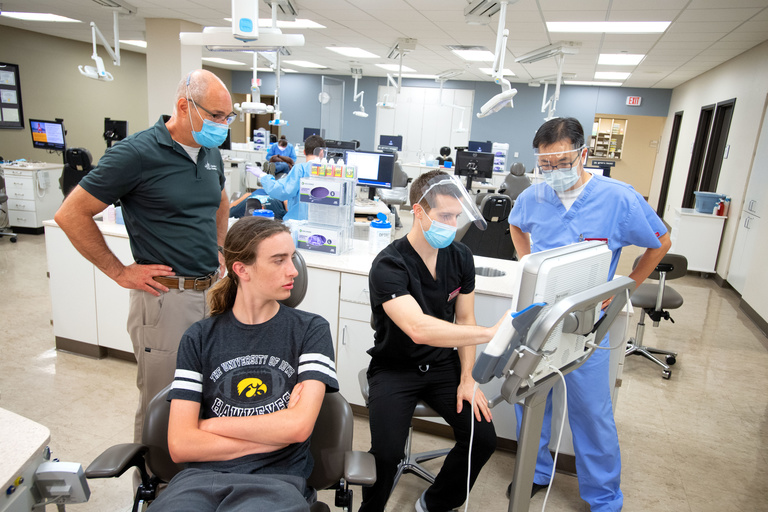 Two orthodontics faculty members overseeing an orthodontics resident treating a patient