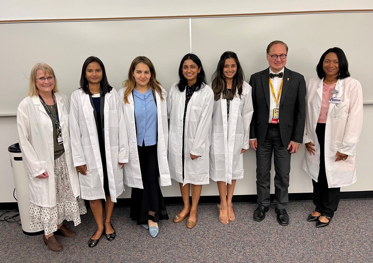 The four ASP students with their white coats standing with Terry Lindquist, Clark Stanford, and Sherry Timmons