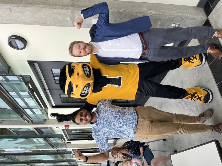 Graduates Ronak Bhagat and William Burns pose with Herky the Hawk