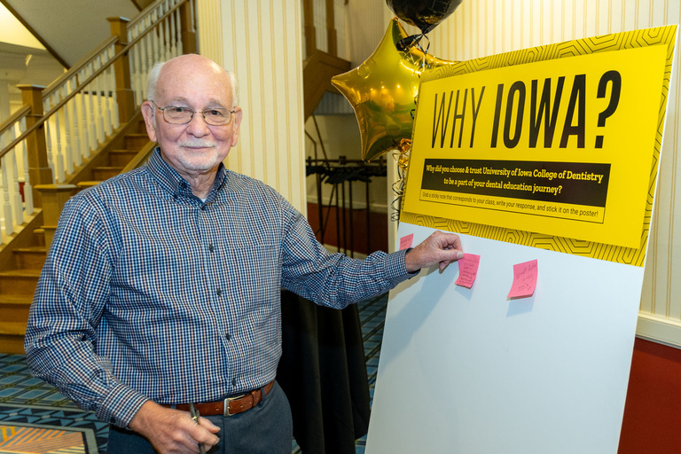 An alum posts their answer to Why Iowa to the "Why Iowa" board at the alumni reception.