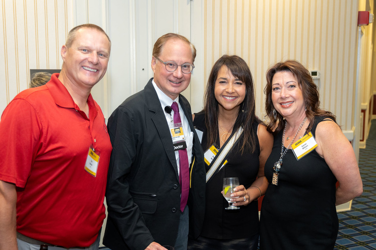 A group of alumni and Dean Stanford take a picture together.