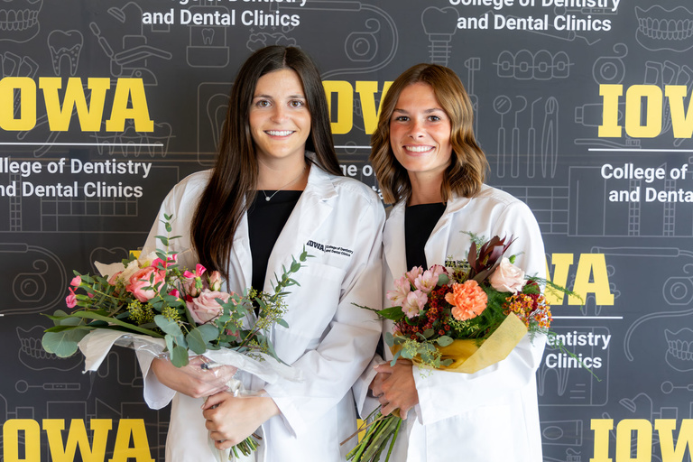 Picture of students posing and holding flowers at White Coat Ceremony Fall 2024