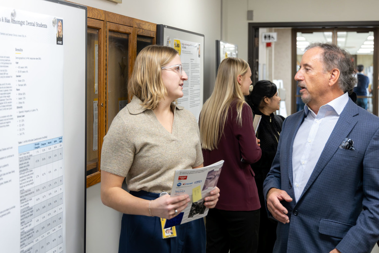 A dental student converses with a faculty member during poster presentations on Feb. 11, 2025.