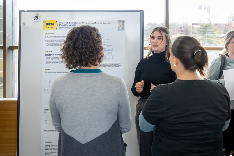 A student researcher shares their work during poster presentations on the 4th-floor link.