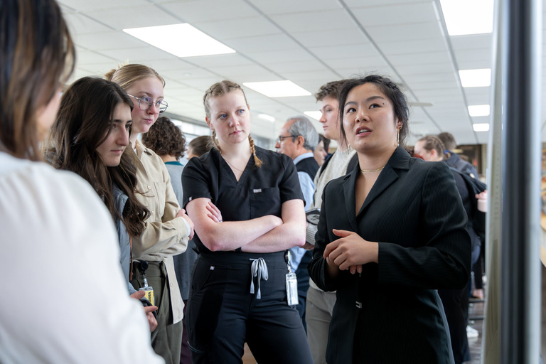 A student researcher shares their work during poster presentations on the 4th-floor link.