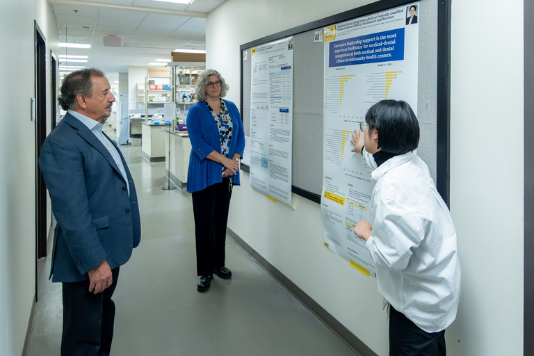 A student researcher shares their work during poster presentations on the 4th floor.