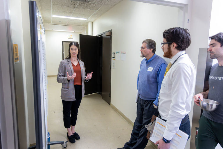 A student researcher shares their work during poster presentations on the 4th-floor.