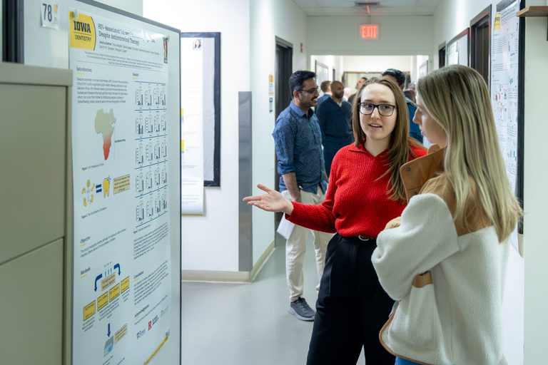 A student researcher shares their work during poster presentations on the 4th floor.