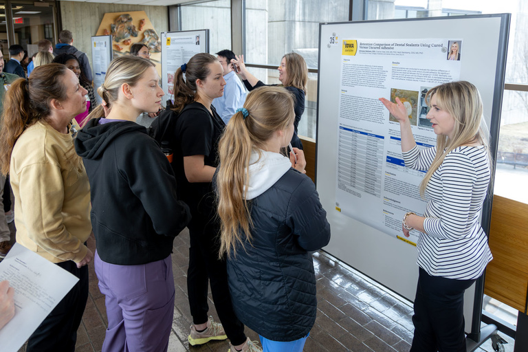 A student researcher shares their work during poster presentations on the 4th-floor link.