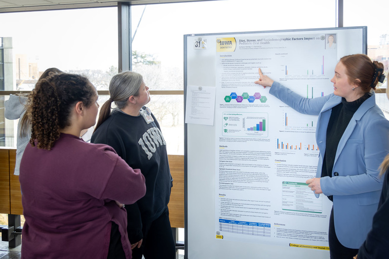 A student researcher shares their work during poster presentations on the 4th-floor link.