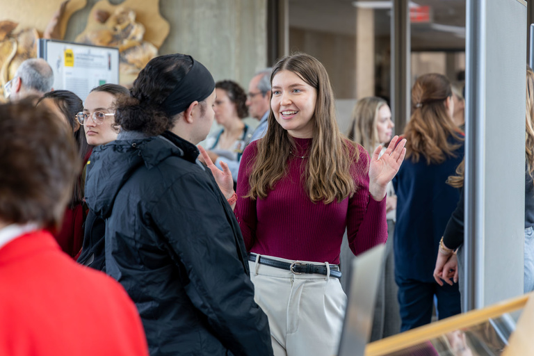 A student researcher shares their work during poster presentations on the 4th-floor link.