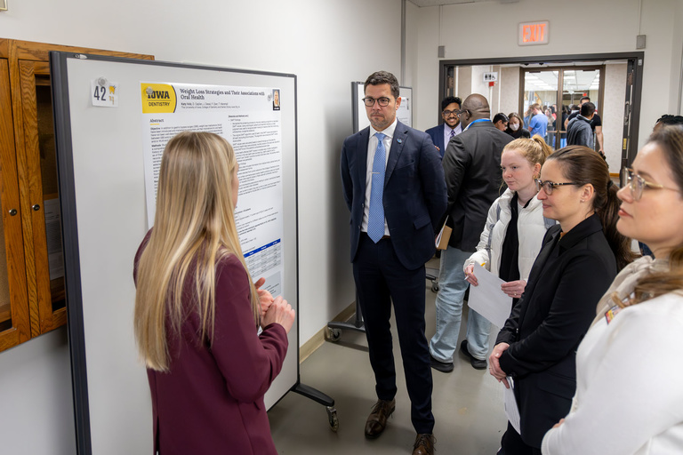 A student researcher shares their work during poster presentations on the 4th floor.