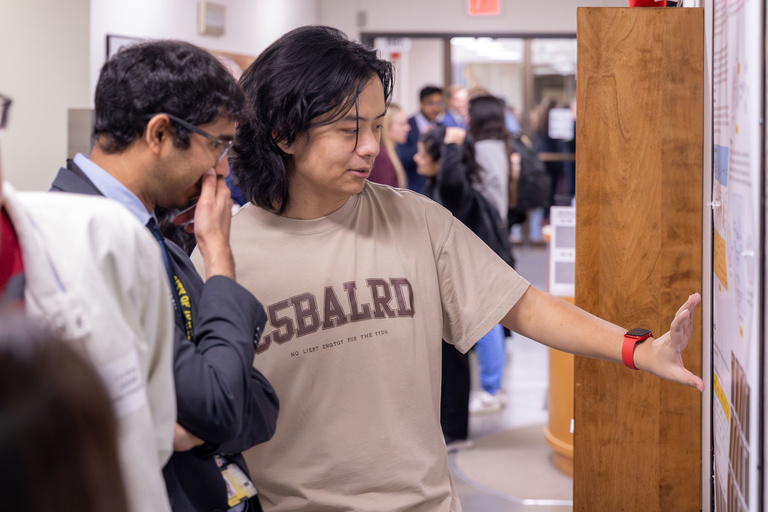 A student researcher shares their work during poster presentations on the 4th floor.