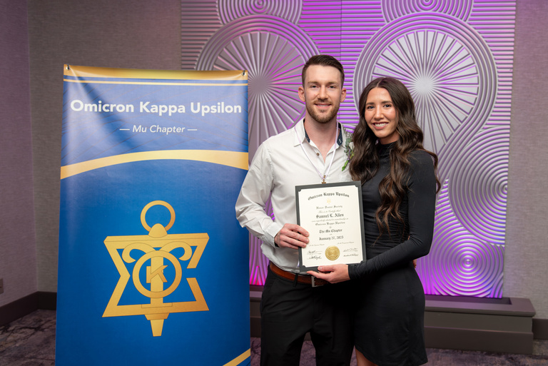 Samuel Allen takes a picture with his partner after being inducted into OKU.