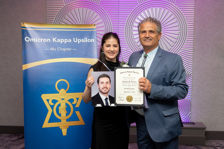 Representatives on behalf of Reuben Lucero accept a certificate inducting him into OKU at the OKU Reception.