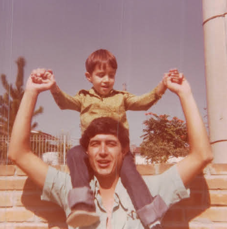 A childhood photo of Leo sitting on his father's shoulders.
