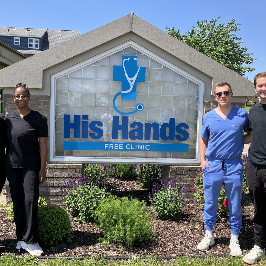 Students volunteered at His Hands Dental Clinic in Cedar Rapids. This is a picture of students posing in front of the clinic's sign.