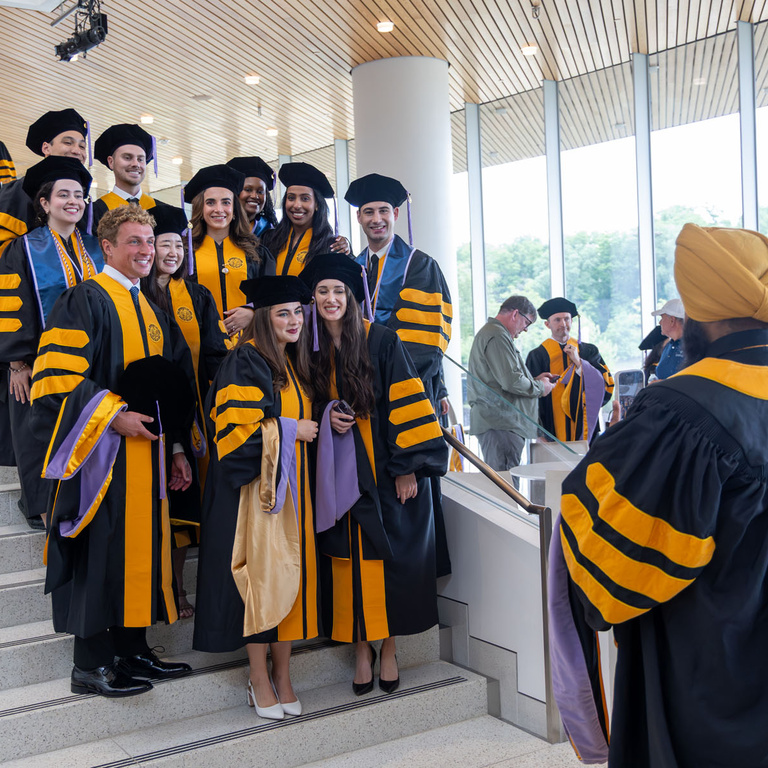 A group of graduates pose for a photo by one of their classmates.