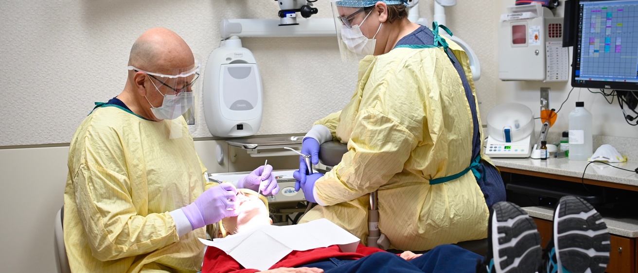 A dentist and assistant with a patient in the dental chair
