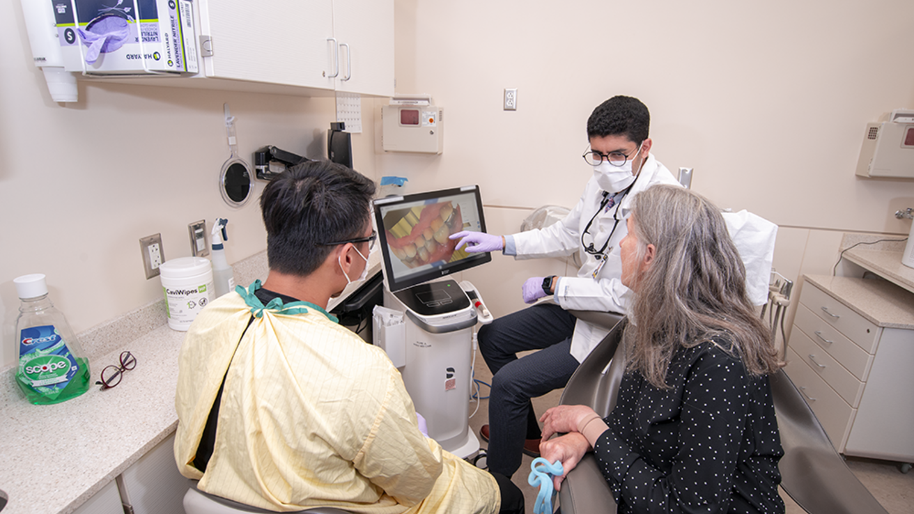 A dental faculty and dental student speaking with a patient